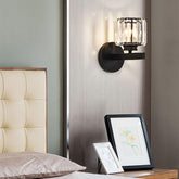 Modern wall sconce on a neutral wall with a bed and framed pictures in the foreground.